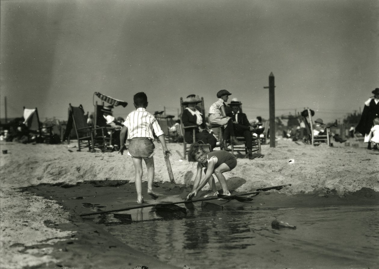 Duas crianças brincam com restos de madeira em águas rasas, Coney Island, c.1910-21 de William Davis Hassler