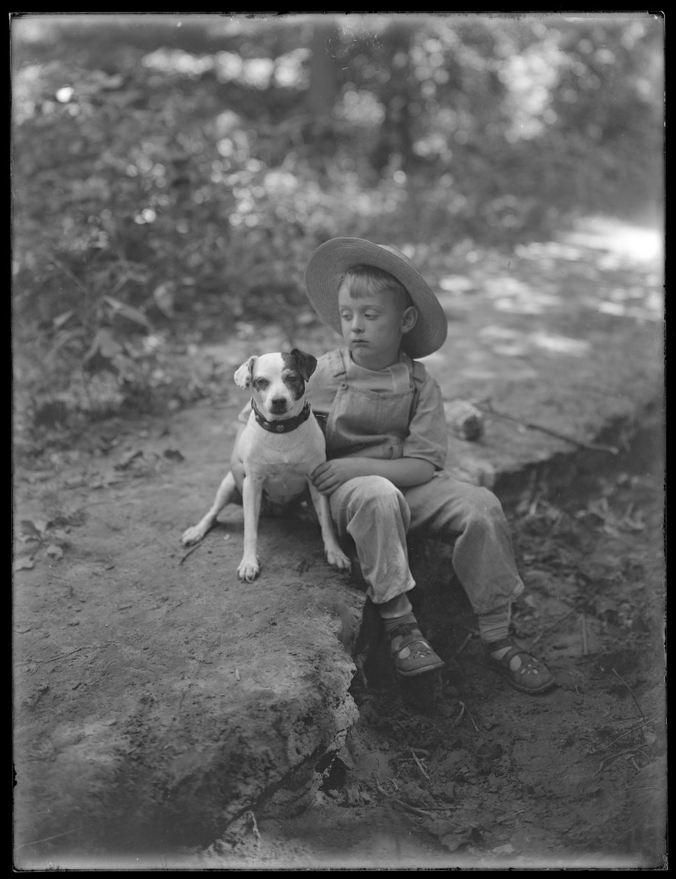 William Gray Hassler de chapéu de palha e macacão, posou sentado na floresta com um cachorro pequeno (Bessie), 20 de agosto de 1911 de William Davis Hassler