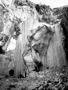 Escavadoras a trabalhar ao longo de uma parede íngreme de uma pedreira de mármore nos Alpes Apuanos, Toscana. (foto a p/b)