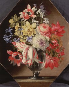 Um vaso de vidro de flores em uma borda de pedra contendo tulipas, crisântemos, rosas e campainhas