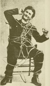 O jovem Harry Houdini a fazer um truque de fuga à corda em 1898 (fotografia a preto e branco) de American Photographer