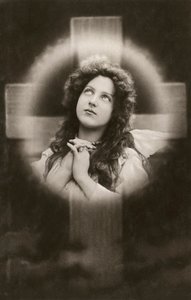 Mulher devota a rezar diante de uma cruz de American School