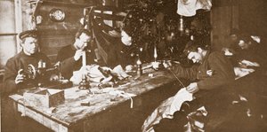 Na cabana durante o meio do Inverno, os homens que se dedicavam à costura de peles para vestuário a ser utilizado em trenós primaveris, pub. Londres 1907 (foto a p/b) de Anthony Fiala