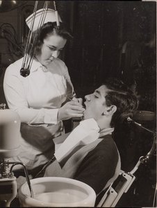 [O higienista dentário inspecciona a boca de um paciente]. de Arnold Eagle