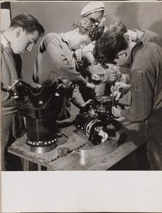 [Cinco jovens trabalham à volta de uma bancada de trabalho].