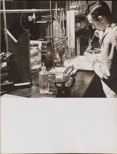 [Um homem num laboratório usa as duas mãos para colocar uma pipeta grande num copo]. de Arnold Eagle