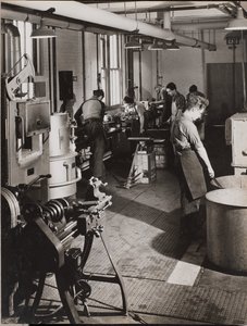 [Seis homens trabalham numa oficina de soldadura].