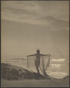 [Vista traseira de uma bailarina que usa um fato transparente na praia]