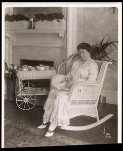 Sra. Howard sentada com um livro em uma cadeira de balanço em sua casa em 200, 5th Avenue, Nova York, 1915-6 (impressão em gelatina de prata)