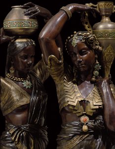 Detalhe de duas tochas de bronze no formato de mulheres indianas carregando vasos