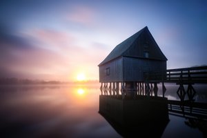 Nascer do sol na casa de barcos enevoada de Christoph Schaarschmidt