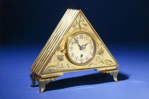 Um relógio de mesa triangular de latão com decoração floral gravada (latão) de Dagobert (attr. to) Peche