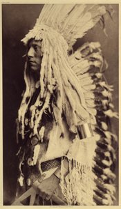 Pessoa idosa, Piegan. Os jovens não perdem nenhuma ocasião de festas públicas para vestirem as roupas do seu pai guerreiro. Foto tirada do volume 6 da enciclopédia publicada por Edward S. Curtis (1868-1952) sobre os índios da América do Norte, com um desta de Edward Sheriff Curtis