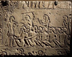 Um grupo de prisioneiros negróides rodeados por guardas armados com bastões enquanto um escriba redige um relatório, relevo do túmulo de Horemheb em Saqqara de Egyptian 18th Dynasty