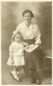 Menina bonita, mãe ou governanta, mostrando fotos para criança pequena (foto a p/b) de English Photographer