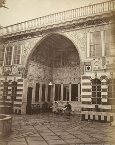 Interior de uma casa judaica em Stambouli, na Síria. Duas mulheres são mostradas debaixo de um pórtico. de Félix Bonfils