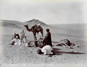 Cameleiros egípcios durante uma pausa no deserto. Em primeiro plano, dois membros do pequeno grupo parecem estar rezando