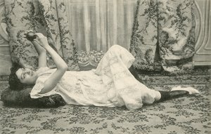 Menina, deitada no chão, segurando uma bola acima da cabeça (foto a p/b) de French Photographer