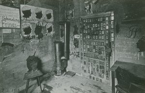 Uma sala com paredes cobertas de graffitis que fazem referência a figuras contemporâneas importantes como Bussche e Waldow. Cartão postal enviado em 1913. de German Photographer