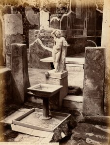 Uma fonte composta por uma escultura de um rapazinho nu. A fonte está na Casa de Balcone pensile, em Pompei.