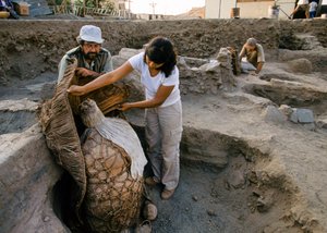 Arqueólogos com uma trouxa de múmia encontrada no local de escavação da escola, 2001 (foto) de Ira Block