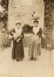 Duas jovens mulheres vestindo roupas tradicionais e carregando jarros de terracota perto de um poço, Marche, Itália, cerca de 1910 de Italian Photographer