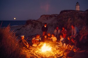 Amigos reúnem-se à volta de uma fogueira de verão no Farol de Great Point. Ilha de Nantucket,,... de James L Stanfield