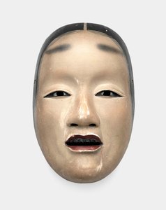 Uma máscara de madeira com fundo de gofun, pintada com sumi para os cabelos, olhos e dentes e vermelha para os lábios de Japanese School