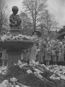 Crianças a colocar ramos de narcisos na fonte com uma estátua no topo de Joseph Hardman
