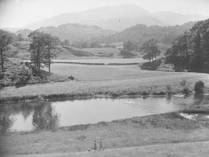 Mulheres a empurrar um bebé num carrinho de bebé na margem próxima do rio, através de um prado, com pessoas a nadar no rio e um agricultor a trabalhar num trator nos campos e nas montanhas ao fundo de Joseph Hardman