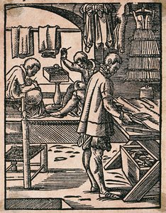 Um alfaiate corta tecido com tesouras enquanto os seus colegas cosem a uma bancada. Xilogravura de J. Amman. de Jost Amman