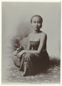 Retrato de estúdio de uma jovem javanesa sentada num sarongue com motivo batik
