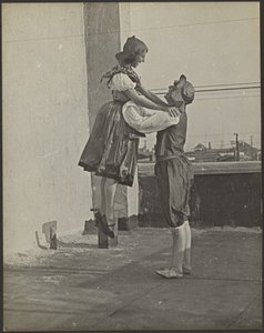 [Homem e mulher a dançar vestidos com trajes tradicionais]