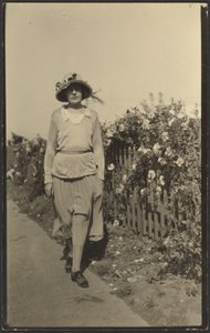[Mulher a caminhar ao longo da vedação com flores]. de Louis Fleckenstein