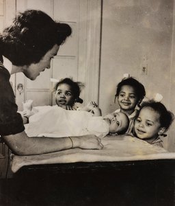 O enfermeiro Henry Street presta assistência a três raparigas afro-americanas no Harlem, em Nova Iorque de Luigi Leoni