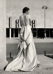 Modelo vista de trás veste um vestido de noite criado pela casa de alta costura "Lamma". O artigo é caracterizado por um lombo baixo e um trem longo. (foto a p/b) de Luis Bogino