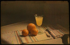Fotografia a cores de uma natureza morta de laranjas frescas e um copo de sumo de laranja tirada com...