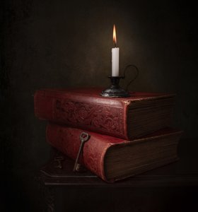Livros à luz de velas e uma chave de Margareth Perfoncio