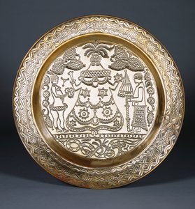 Um carregador de latão Efik em relevo com uma figura feminina vestida no centro e dois servos segurando um leque e um guarda-chuva