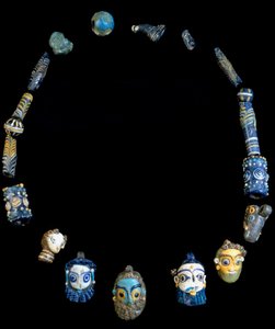 Colar em pasta de vidro com pingentes representando cabeças barbudas, originalmente de Olbia, agora conservado no Museu Nacional Arqueológico de Cagliari
