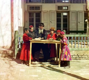 Um grupo de crianças judias com um professor em uma mesa na frente de uma casa, Samarkand, Império Russo, entre 1905 e 1915