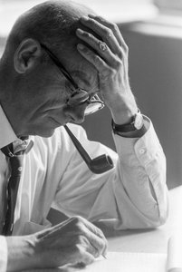 O Dr. Benjamín Viel, médico chileno, estuda um documento e fuma um cachimbo.