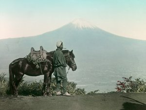 Homem japonês com um cavalo no Monte Otome, de toga, a olhar para o Monte Fuji, cerca de 1900 - 1915 (fotografia) de Teijiro Takagi
