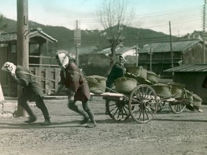 Camponeses japoneses a puxar sacos de arroz numa carroça, cerca de 1900 - 1915 (fotografia) de Teijiro Takagi
