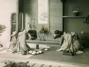 Duas mulheres japonesas em trajes tradicionais cumprimentam-se antes da cerimónia do chá, cerca de 1900 - 1915 (fotografia) de Teijiro Takagi