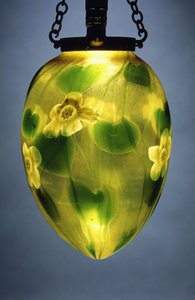 Uma lanterna suspensa, decorada com folhas verdes e trepadeiras e flores amarelas iridescentes,