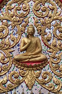 20151102, Vang Vieng, Laos : Porta de entrada ornamentada com relevos dourados. O Buda Ensinante retrata um momento particular na vida do Buda, a saber, o primeiro sermão que o Buda fez depois de alcançar a Iluminação. de Unbekannt
