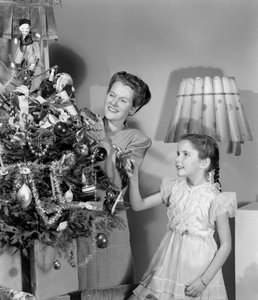 Mulher e menina decorando uma árvore de Natal, c 1948 de Unbekannt