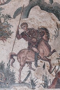 Detalhe do pequeno mosaico de caça. Um caçador está prestes a espetar uma lebre. Século III - IV. Vila Romana do Casale, Sicília. Site da UNESCO. de William M. Timlin