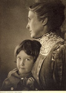 Retrato a meio comprimento de uma criança abraçada com ternura por uma senhora idosa. A mulher posa com o rosto de perfil, segurando o peito do rapazinho. Tem um olhar vivo e atrevido, dirigido para a câmara de Unbekannter Künstler